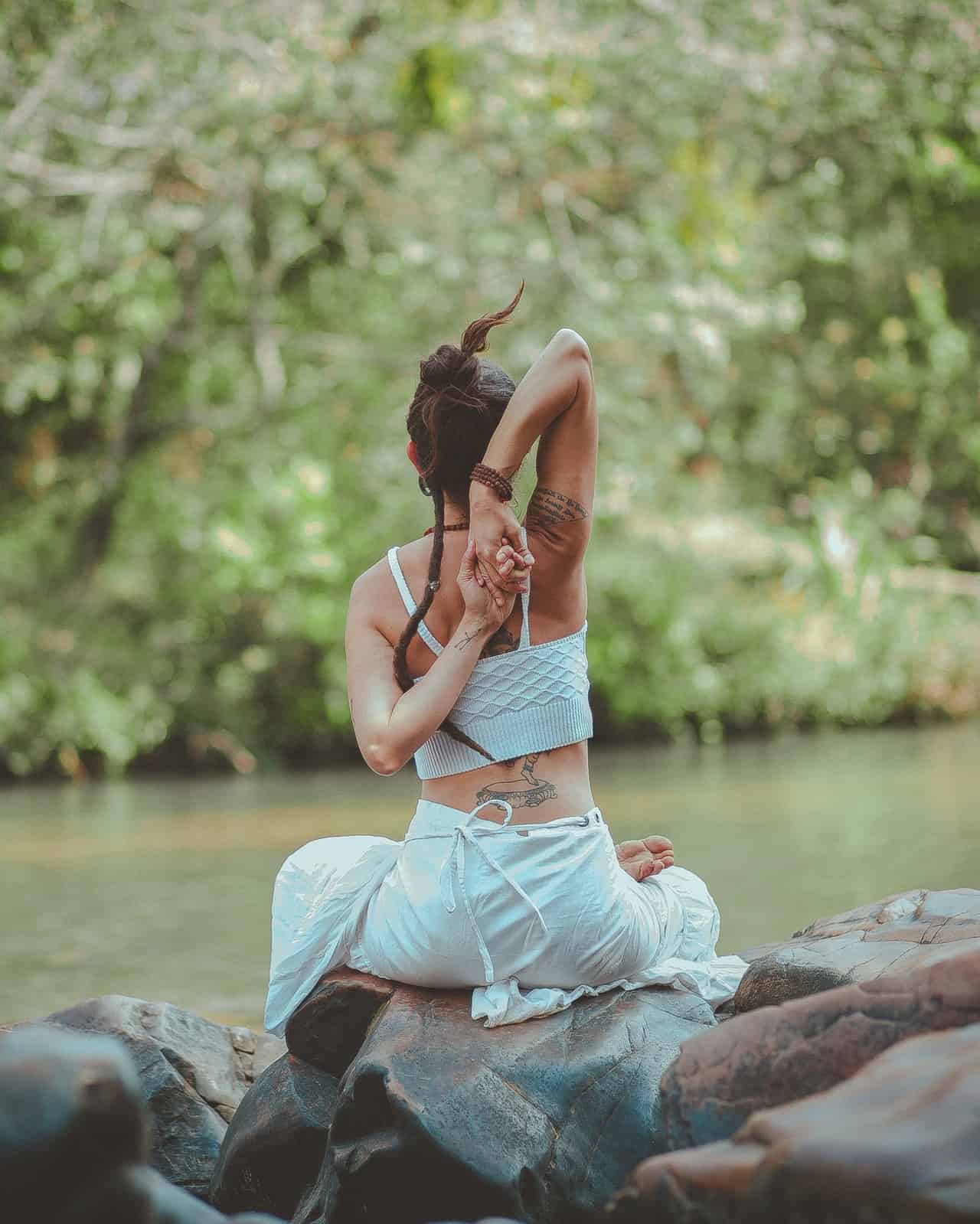 back-view-photo-of-a-woman-sitting-near-body-of-water-doing-yoga